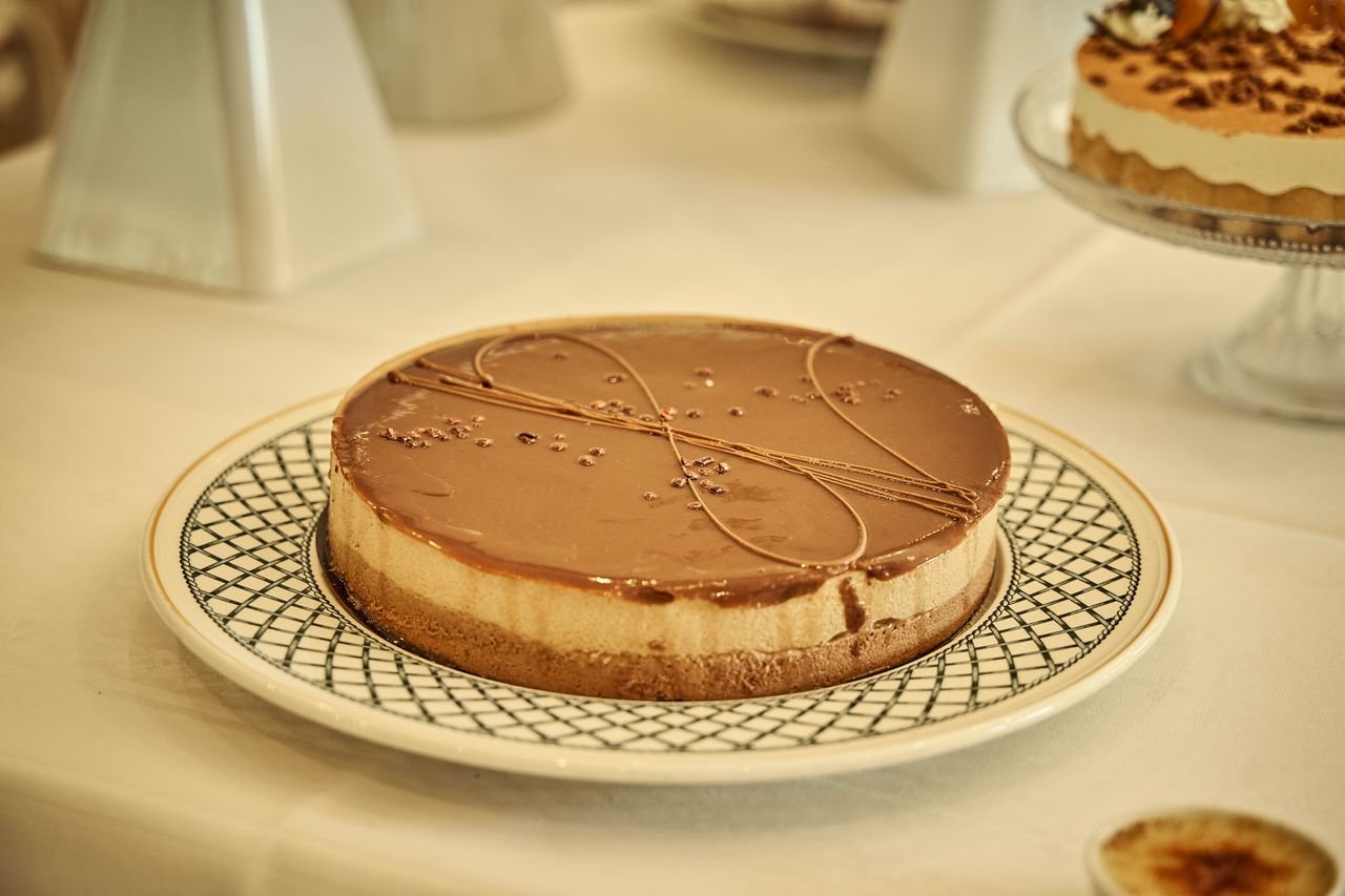 Chocolate glazed cheesecake with intricate design on an elegant plate, perfect for gourmet dessert lovers.