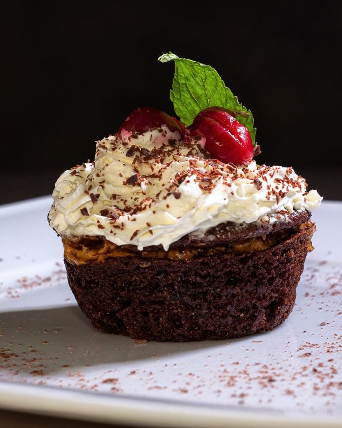 social-feed-img-04 Indulgent chocolate cupcake topped with whipped cream and cherry garnish.