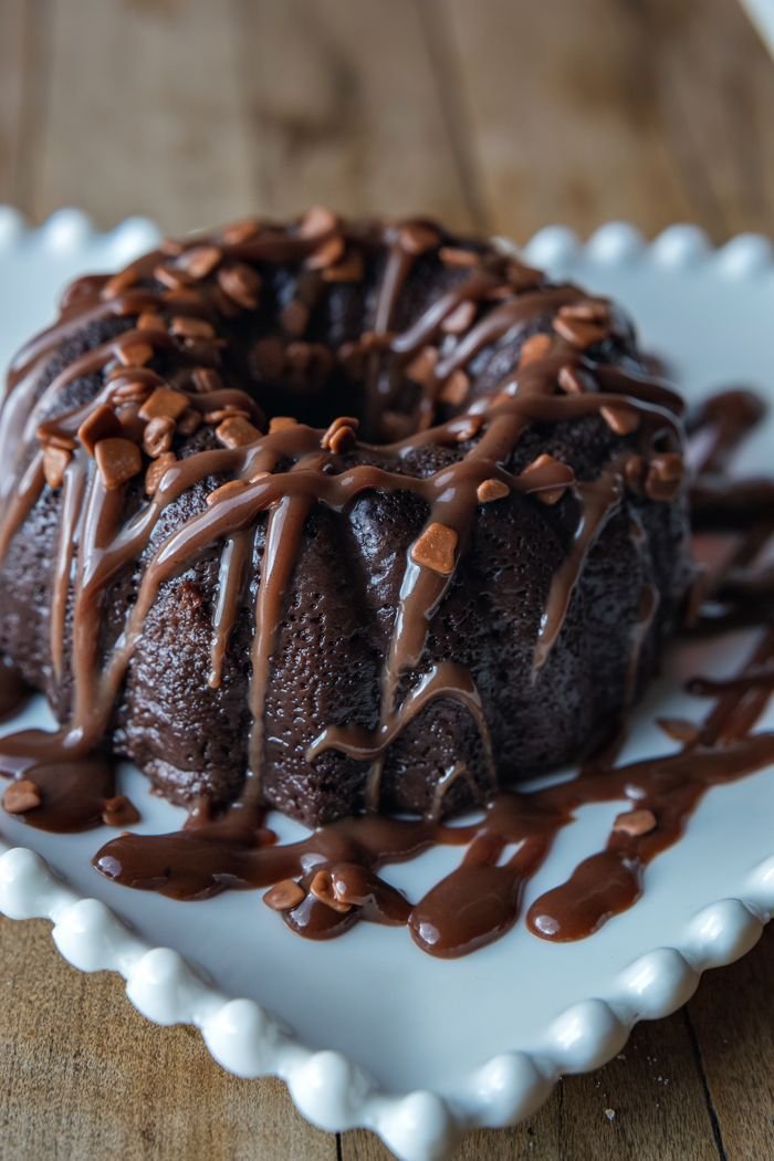 social-feed-img-01 Close-up of a delicious chocolate bundt cake drizzled with rich chocolate sauce on a white plate.